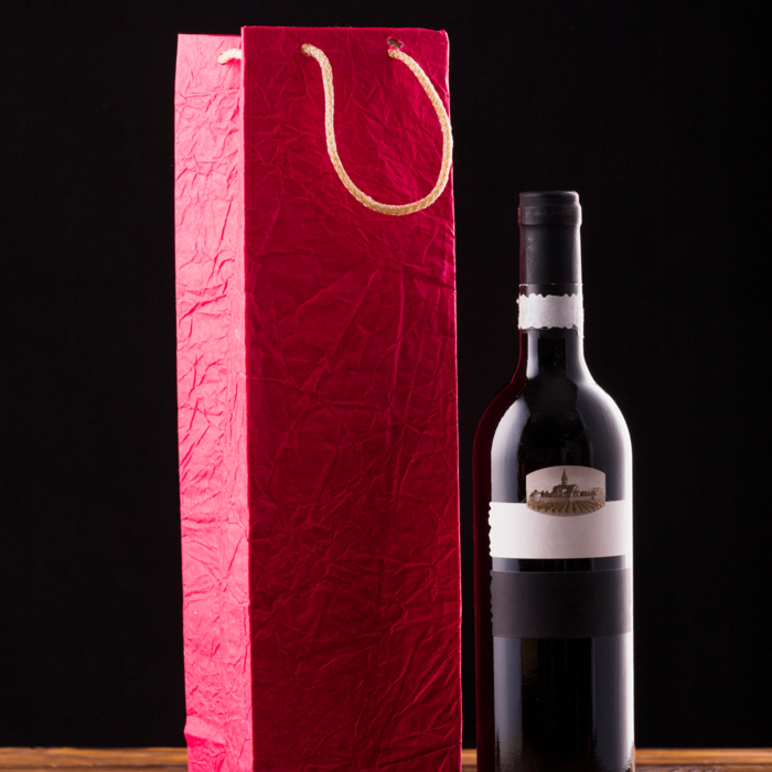 wine-bottle-red-paper-bag-wooden-table-against-black-backdrop