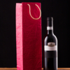 wine-bottle-red-paper-bag-wooden-table-against-black-backdrop